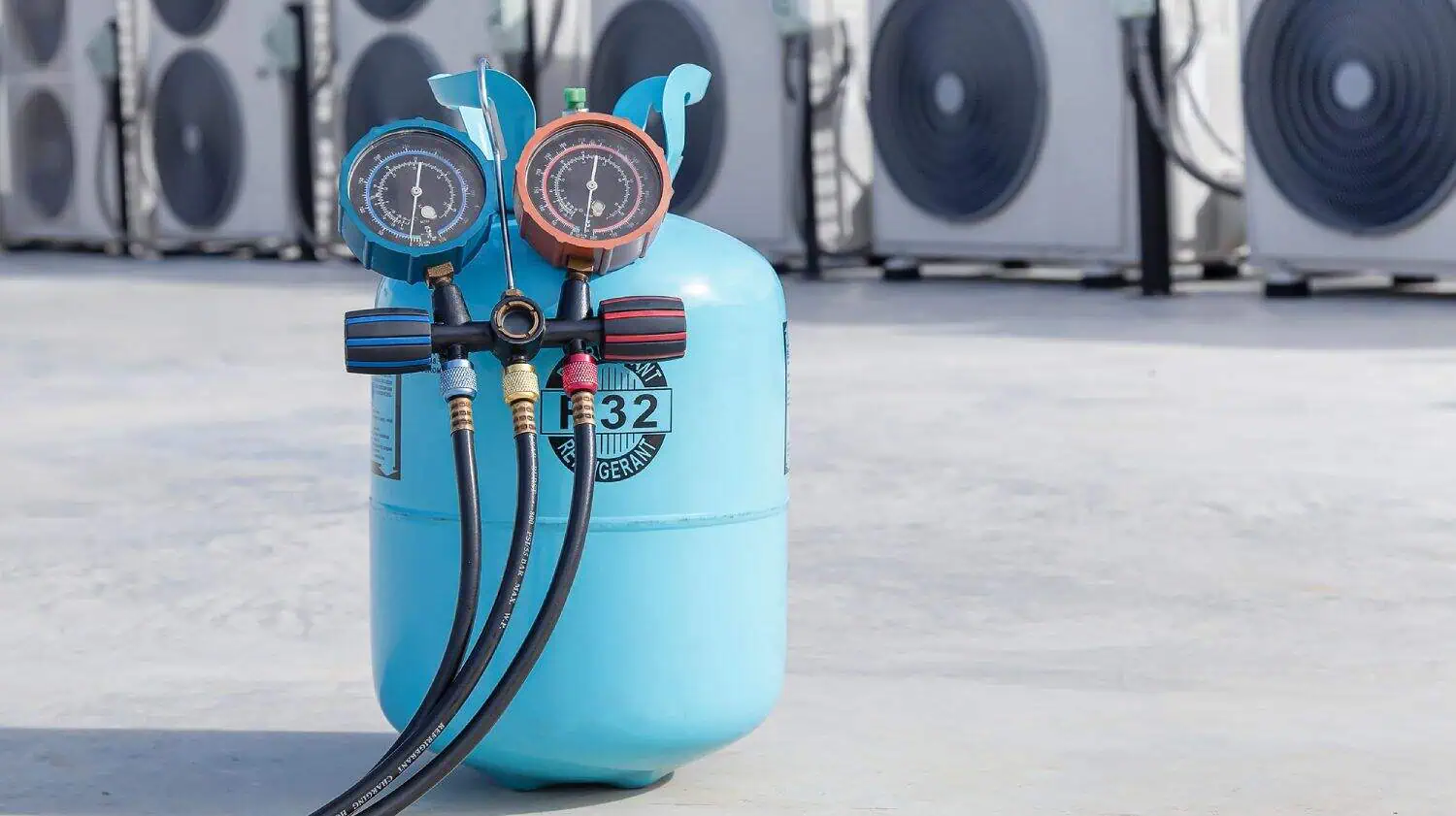 A blue refrigerant tank with pressure gauges attached, positioned in front of several air conditioning units.