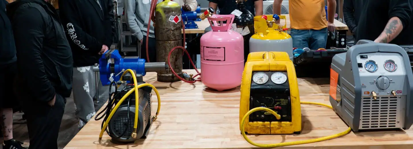 A group of people gathered around a table displaying various gas cylinders, engaged in discussion or examination.
