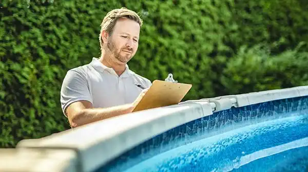 Man inspecting above ground swimming pool with clipboard in hand