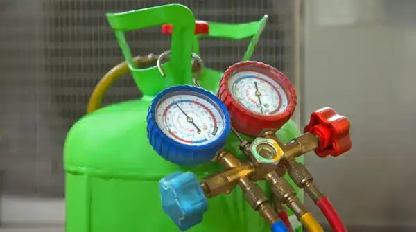Green refrigerant cylinder with pressure gauges and hoses