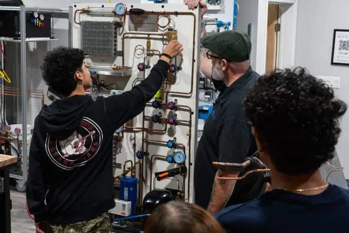 Group examining pipes and gauges, one adjusting a valve