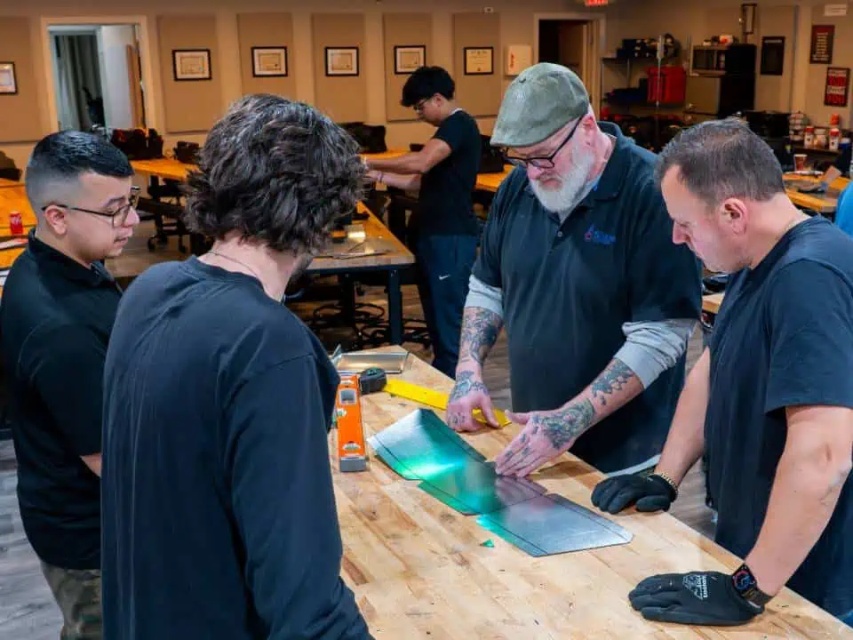Group learning metalworking techniques at a workshop table