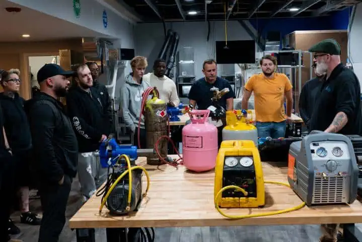 Group observing HVAC equipment demonstration in a workshop setting.