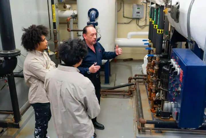 Instructor explaining an industrial mechanical setup to three people