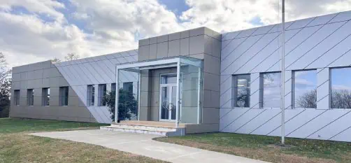 Modern building with glass entrance and paved walkway under a cloudy sky. Modern building with glass entrance and paved walkway under a cloudy sky.