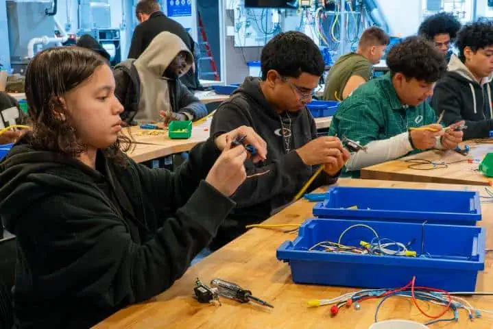 Students working on electronics projects at a workshop table