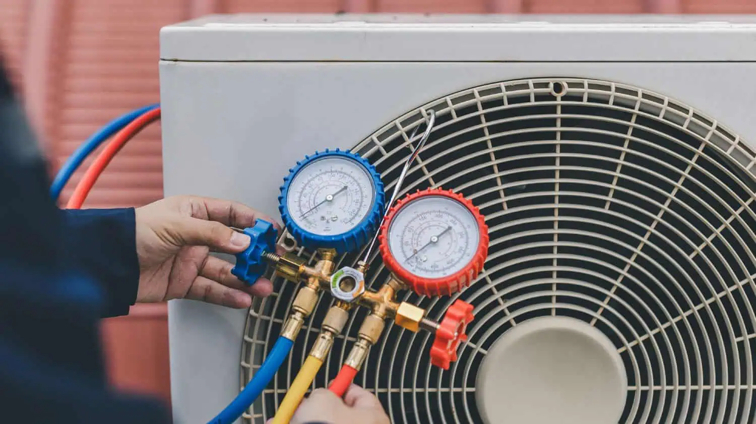 “Technician adjusting blue and red gauges on a refrigerant manifold for an AC unit.