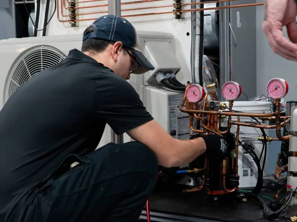 Technician servicing a refrigeration unit with pressure gauges