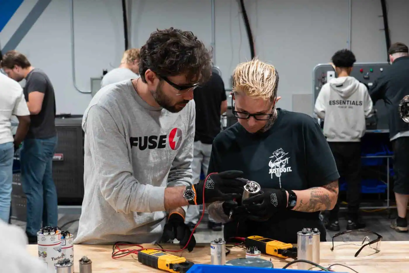 Two people working on electrical components in a workshop