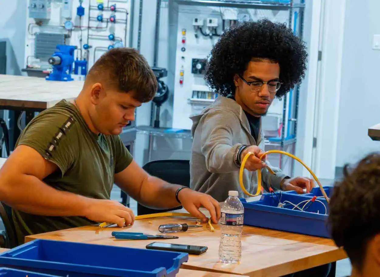 Two-young-men-assembling-materials-with-tools-in-a-workshop-classroom